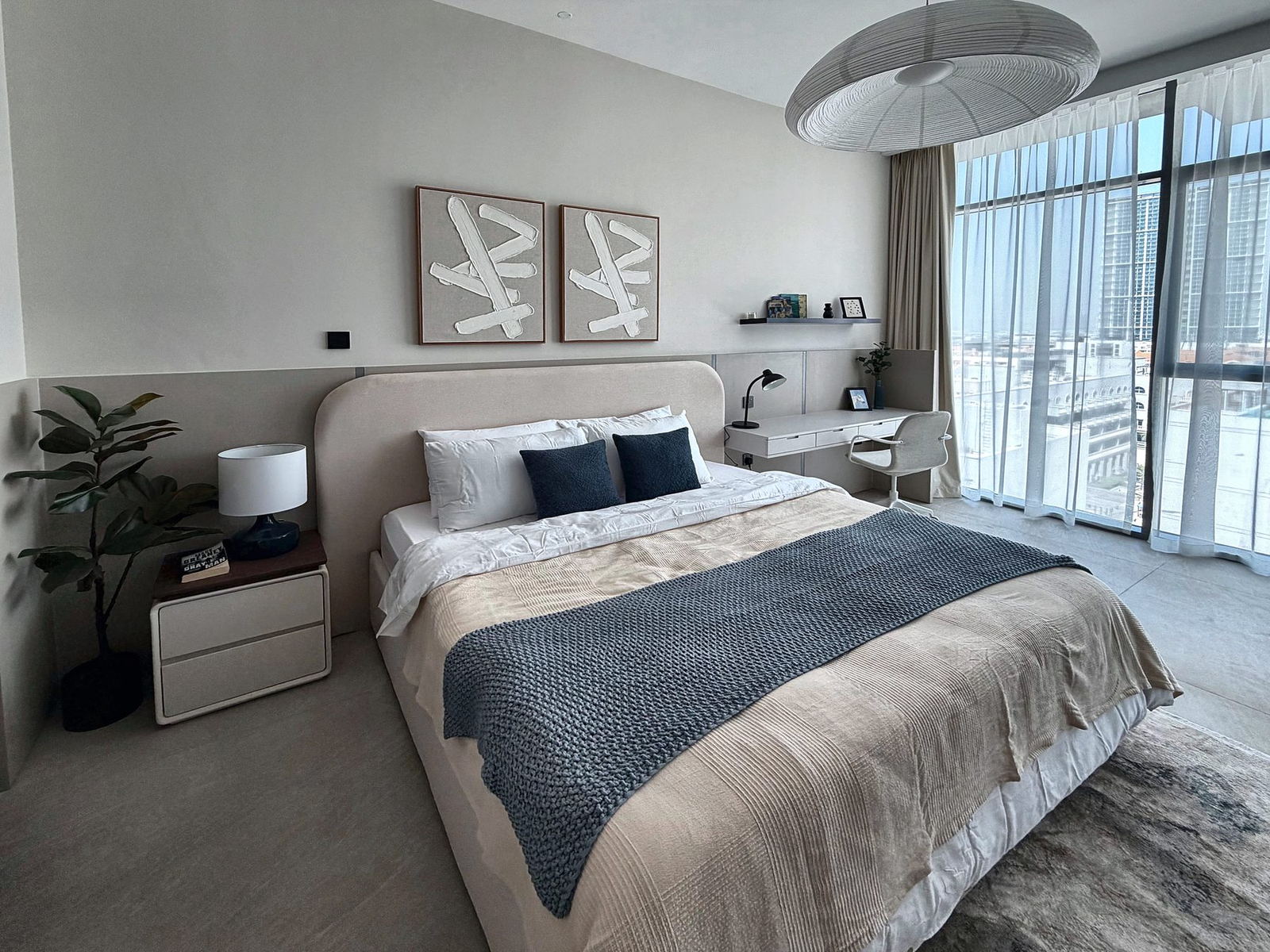Bright bedroom with upholstered bed, plaster artworks, paper pendant and floor-to-ceiling windows