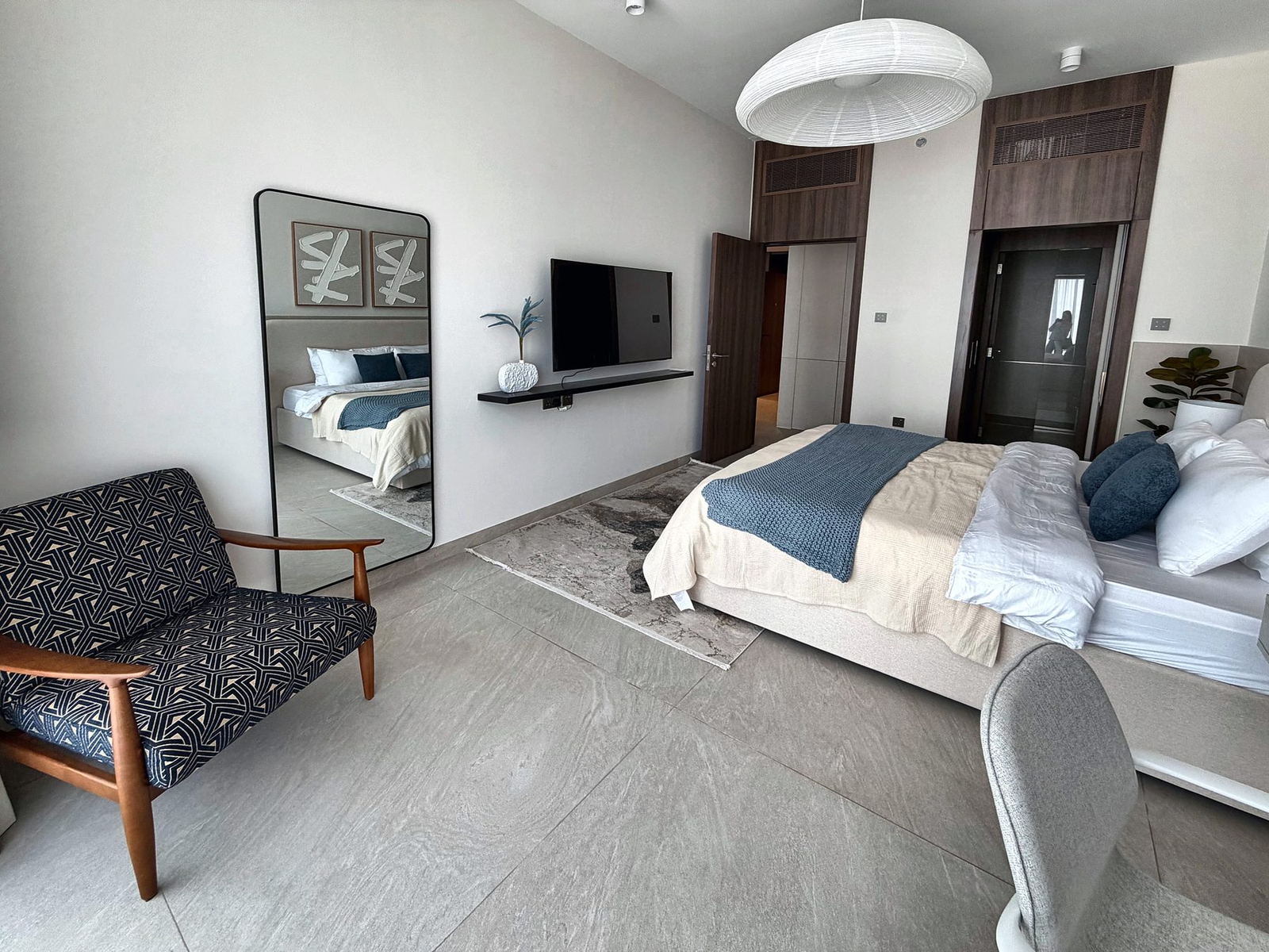 Bedroom corner with patterned navy mid-century chair and full-length mirror
