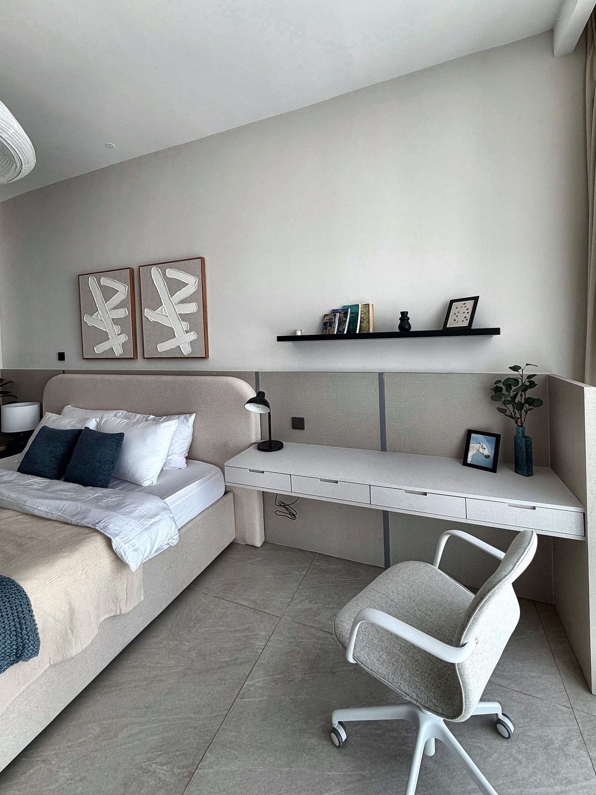 Bedroom workspace with built-in desk, black shelf and textured wall art