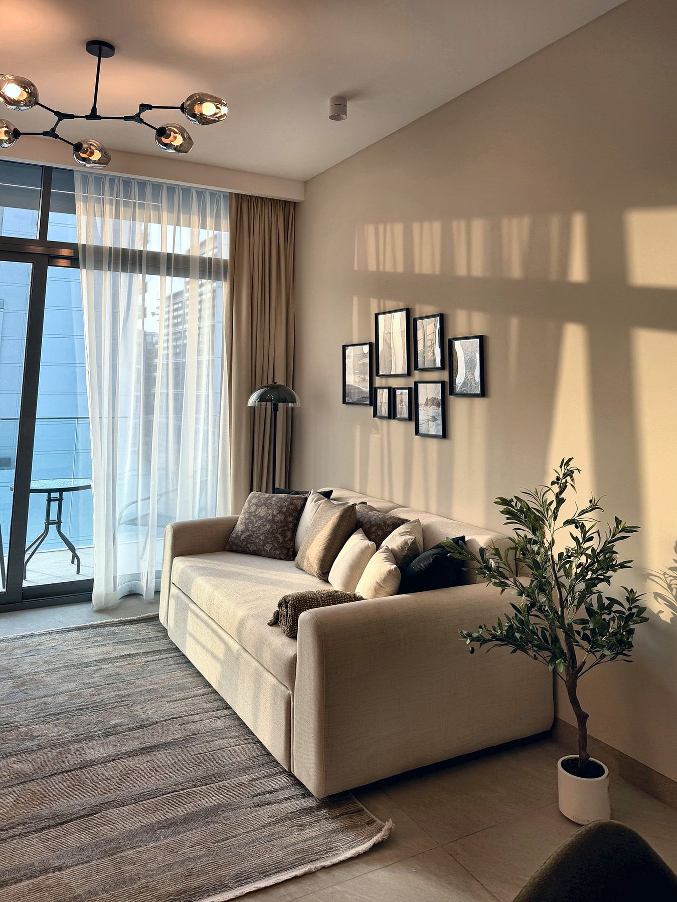 Living room at golden hour with a linen sofa, olive tree and gallery wall, Dubai