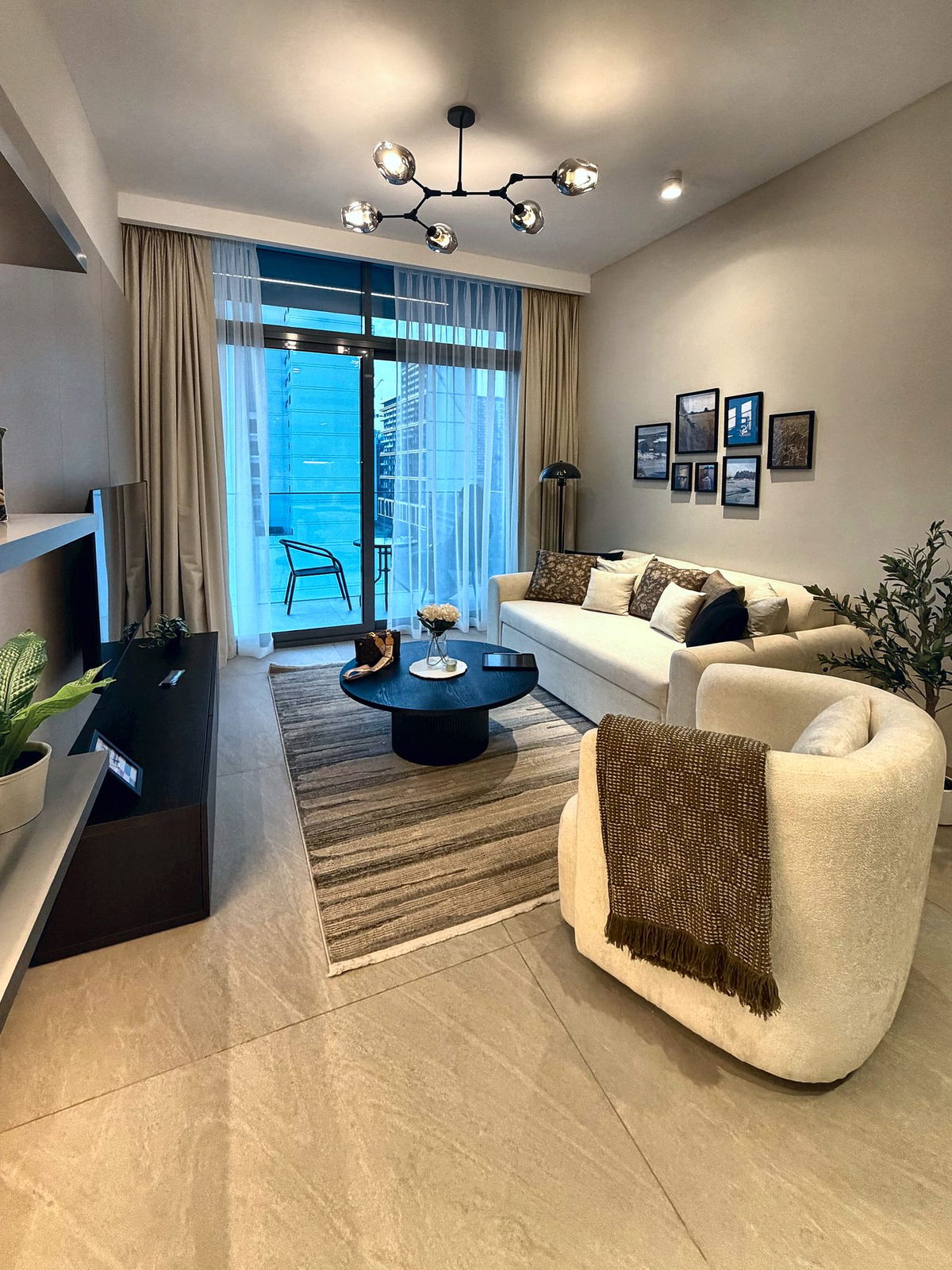 Living room at dusk with boucle armchair, olive throw and city view